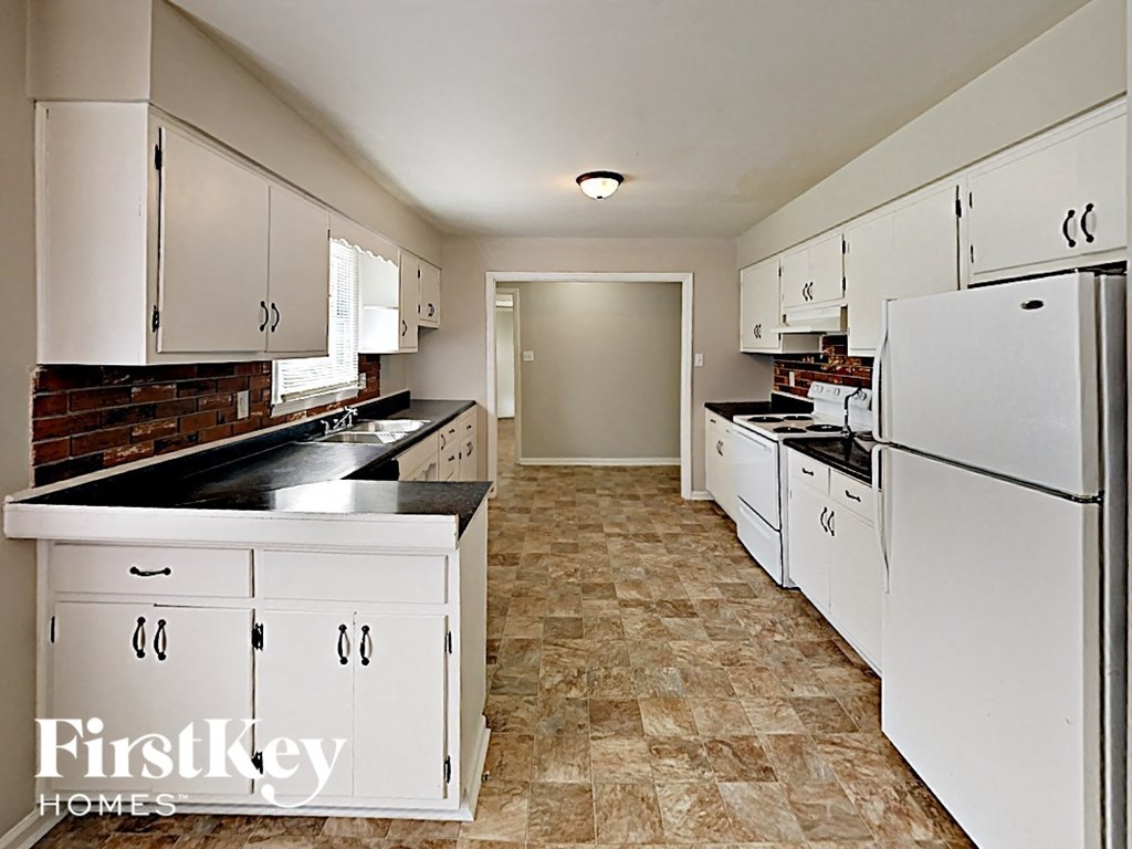 A kitchen with white cabinets and a black counter top.