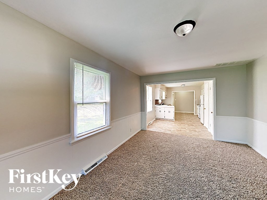A room with a carpet floor and a window with blinds.