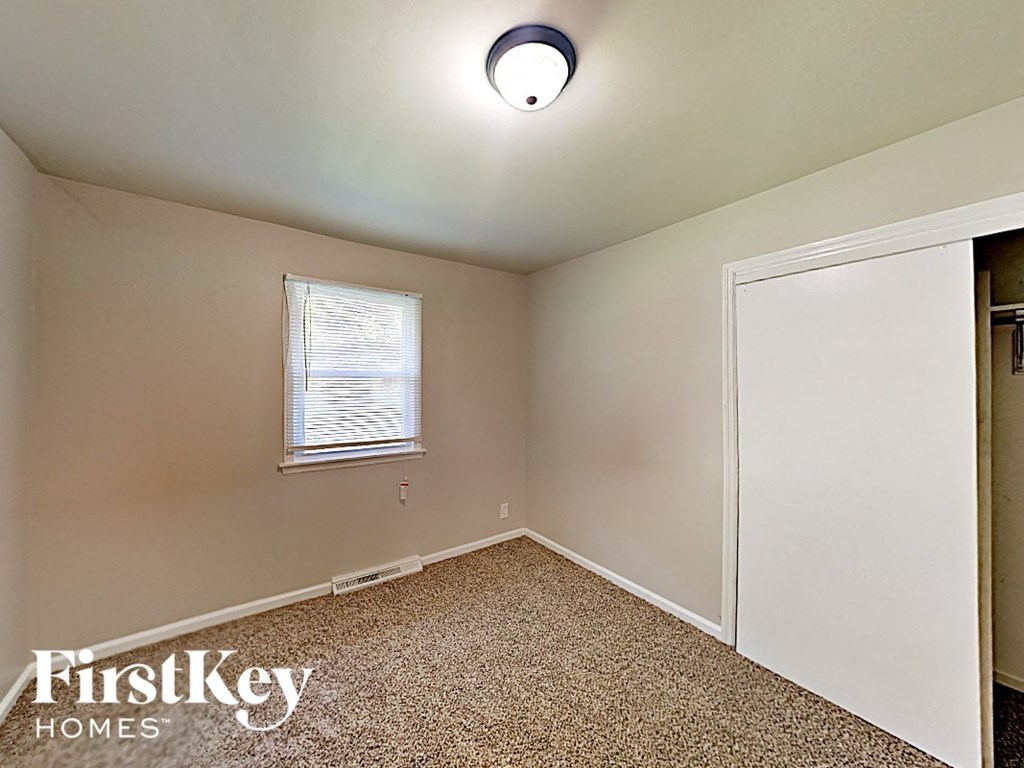 A room with a window and a carpeted floor.