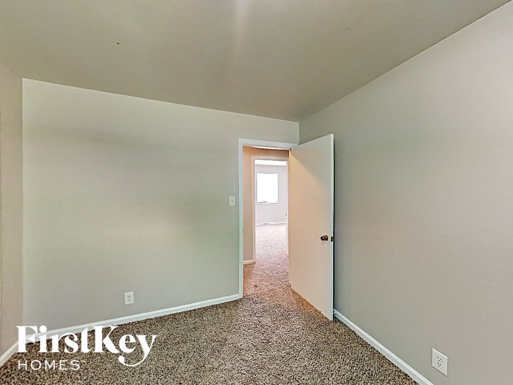 A room with a carpeted floor and a doorway leading to another room.