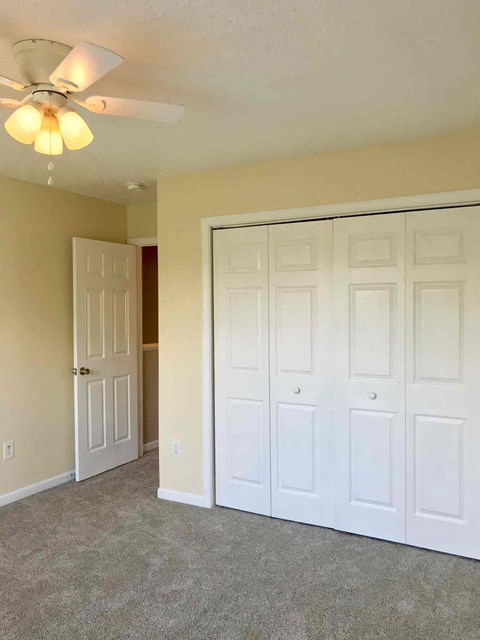 a bedroom with three closets and a ceiling fan