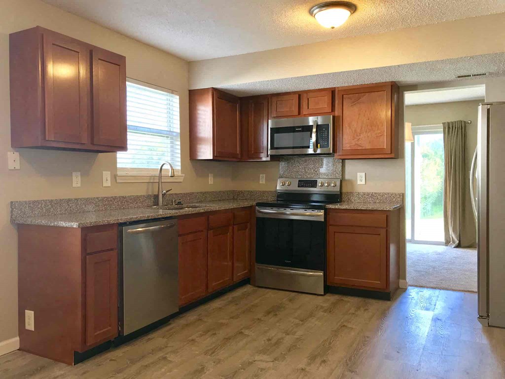 an empty kitchen with wooden cabinets and stainless steel appliances