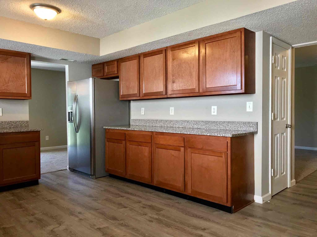 an empty kitchen with wooden cabinets and a stainless steel refrigerator