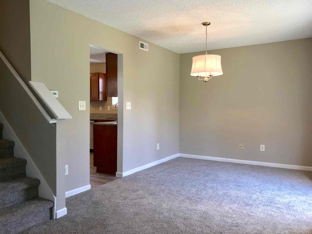 an empty living room with stairs and a lamp