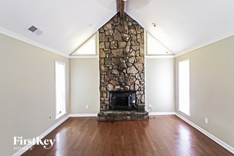 a living room with a stone fireplace and wooden floors