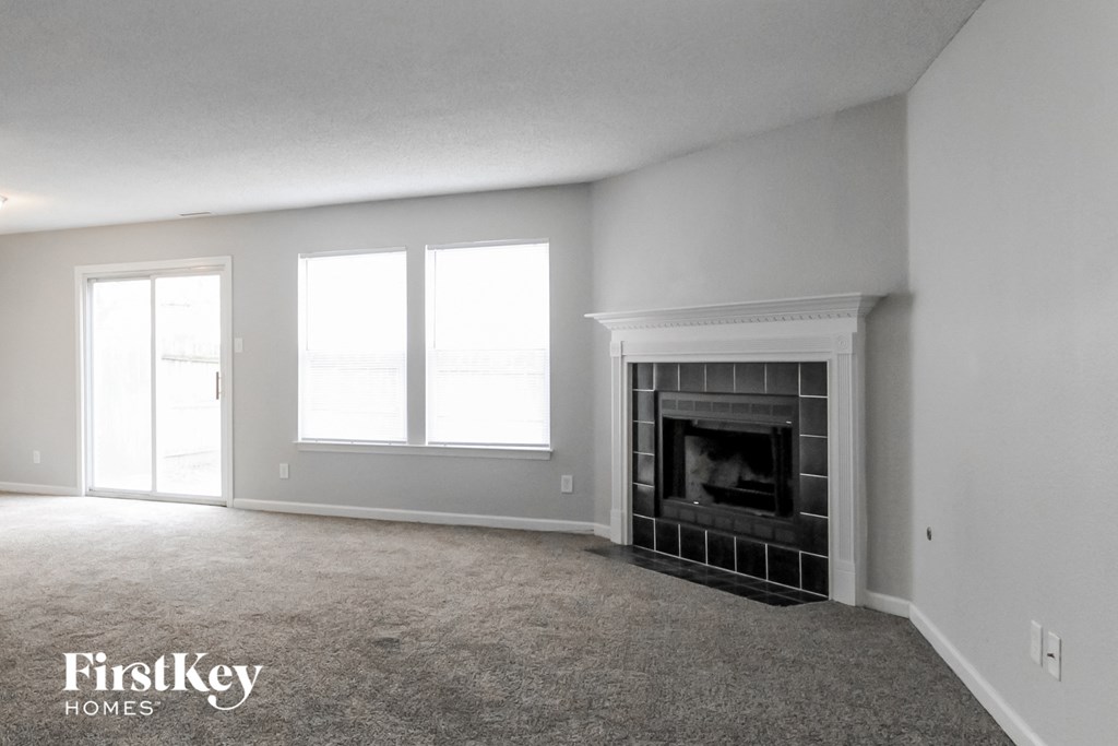 A living room with a fireplace and a carpet.
