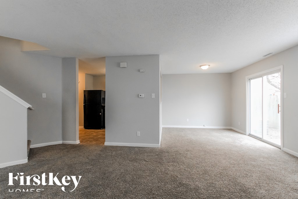 A spacious room with a carpeted floor and a doorway leading to another room.