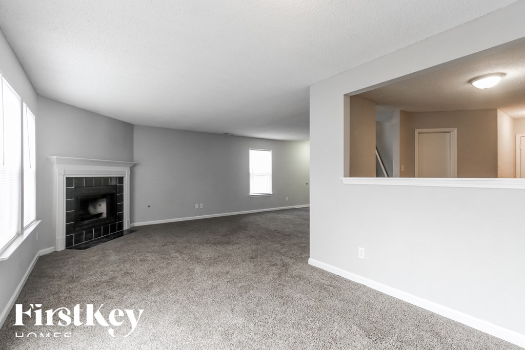 A spacious living room with a fireplace and a carpeted floor.