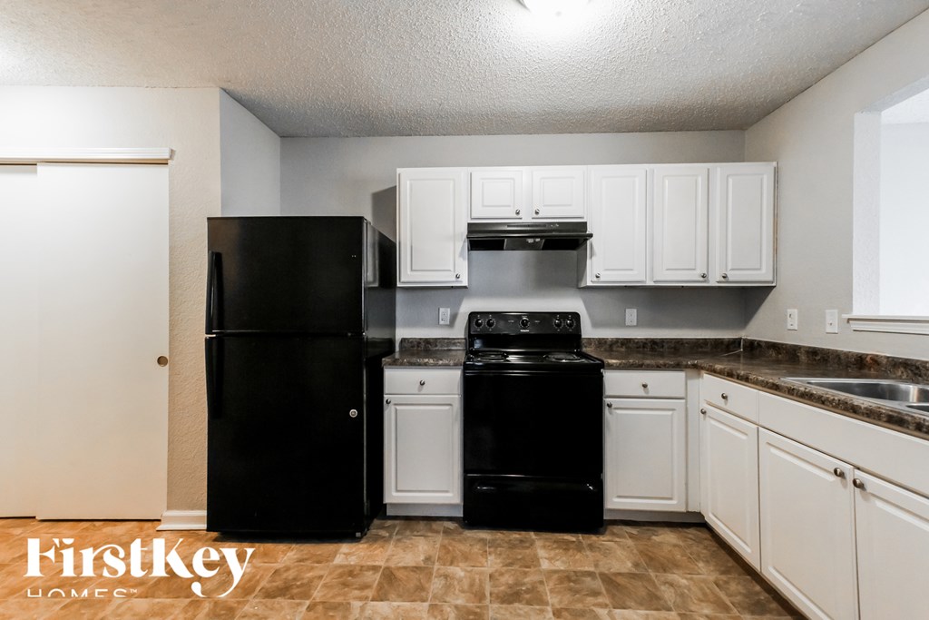 A kitchen with black appliances and white cabinets.
