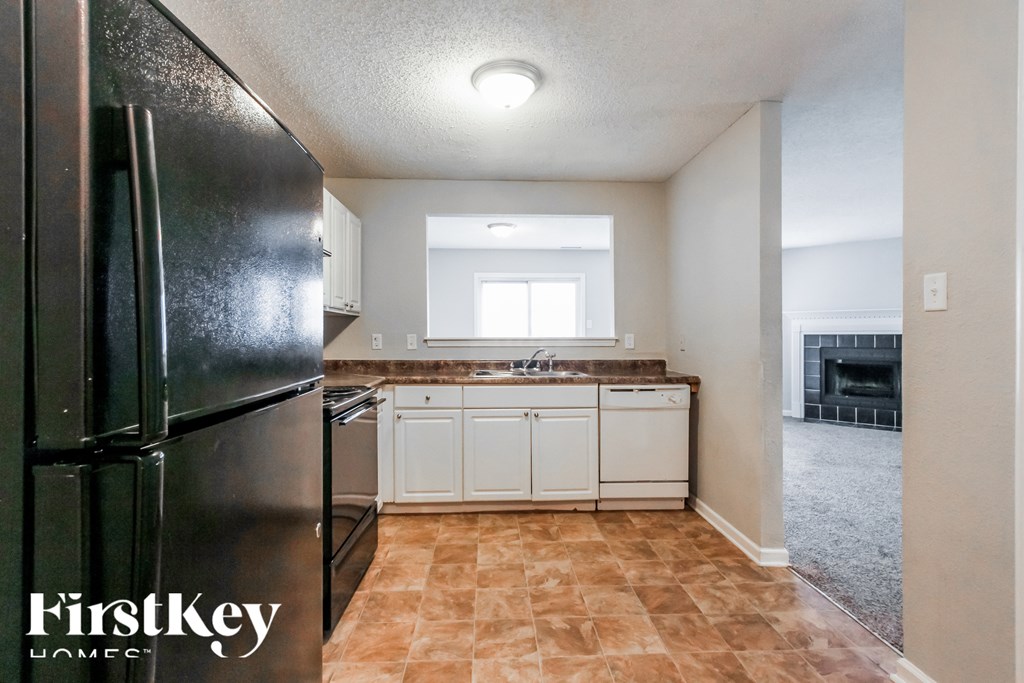 A kitchen with a black fridge and white cabinets.