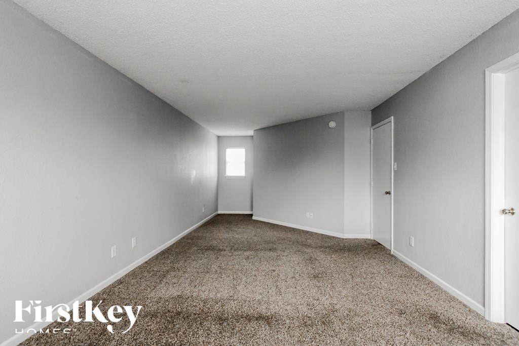 A long, empty hallway with a carpeted floor and white walls.