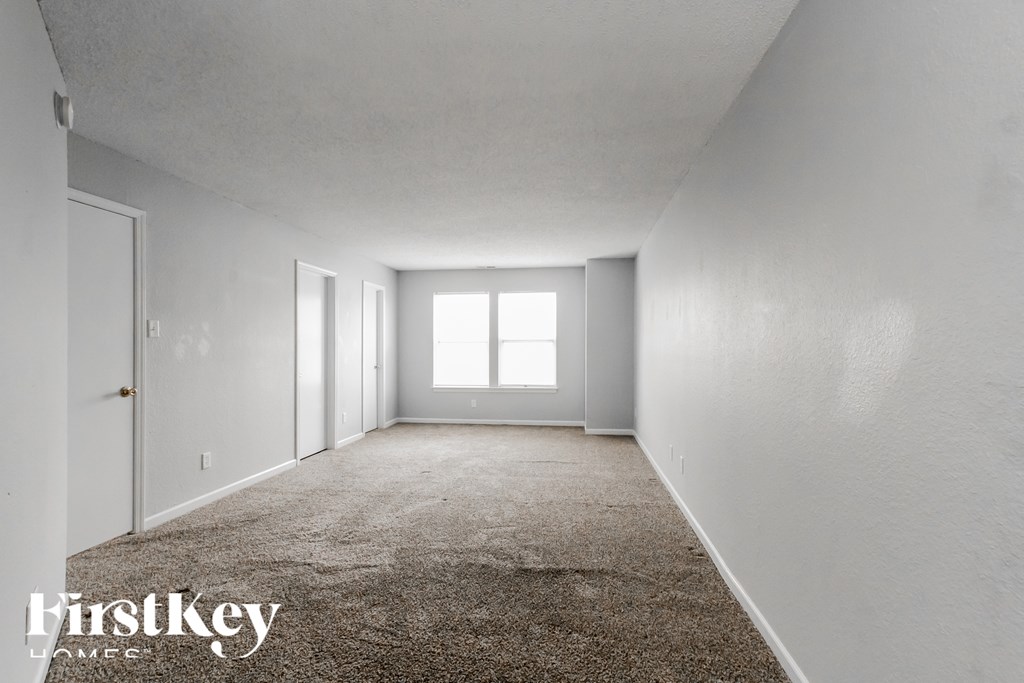 A spacious, empty room with a carpeted floor and white walls.