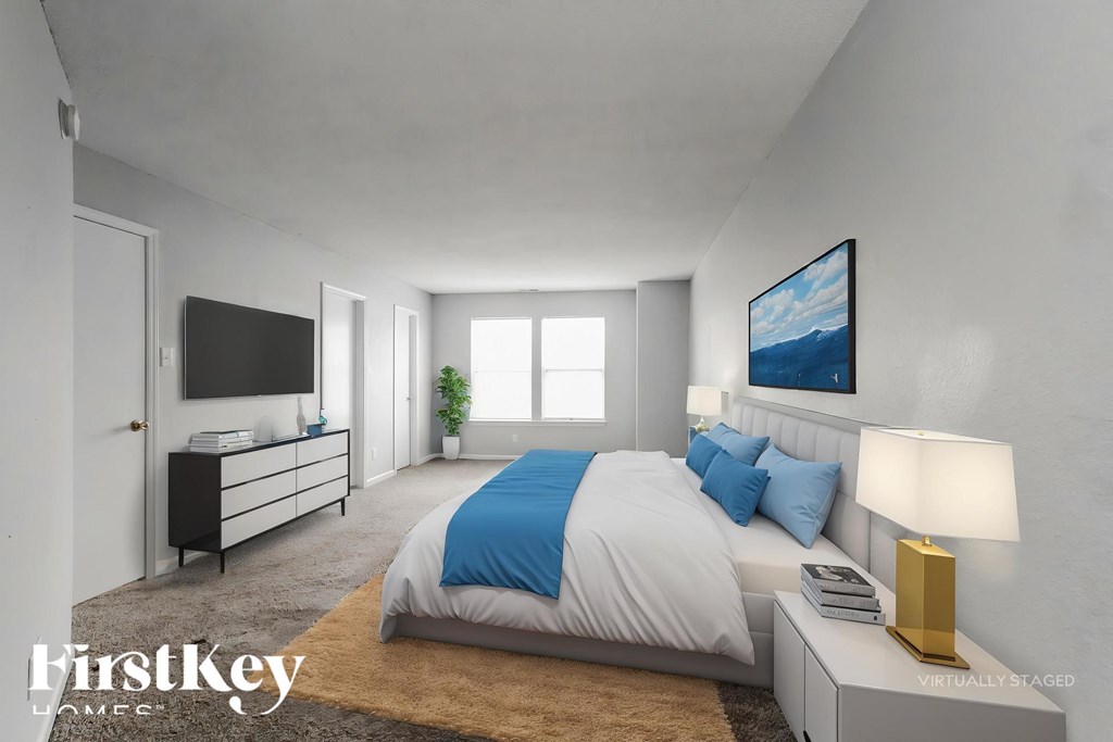 A bedroom with a bed, a television, and a painting on the wall.