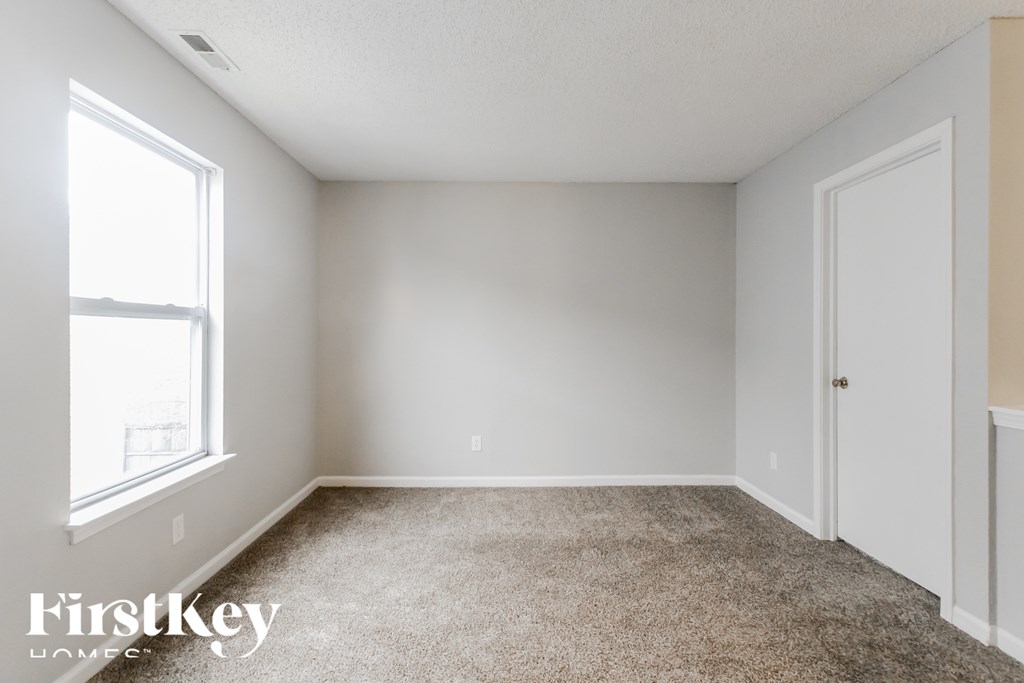 A room with a carpeted floor and a window letting in natural light.