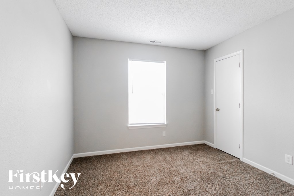 A room with a carpeted floor and a window.