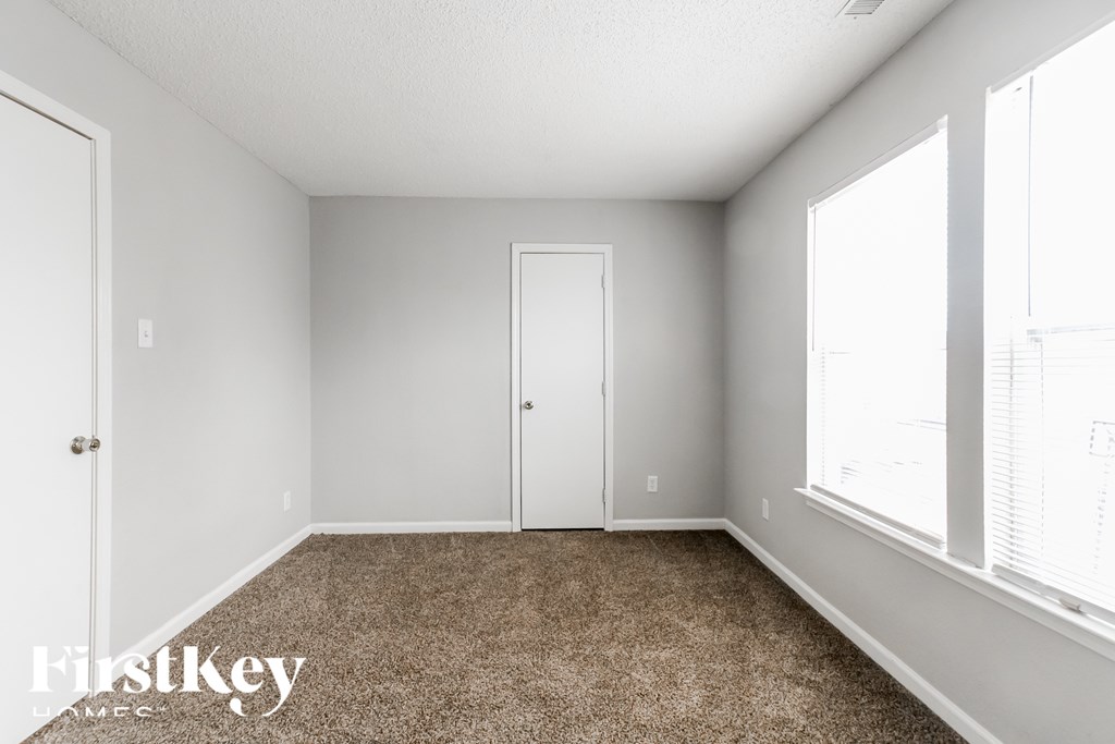 A room with a carpeted floor and a large window.