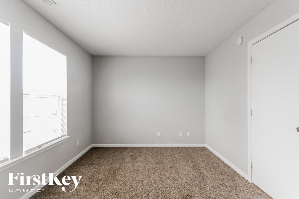 A room with a carpet floor and a door on the right side.