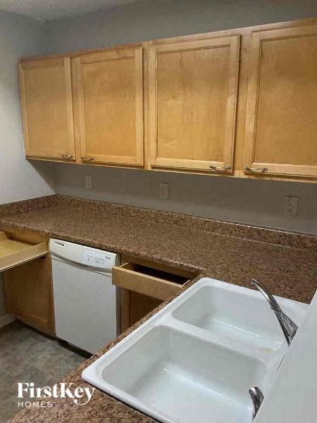 A kitchen with wooden cabinets and a white dishwasher.