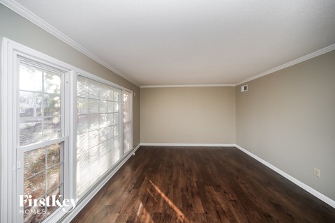 an empty living room with wood floors and a large window