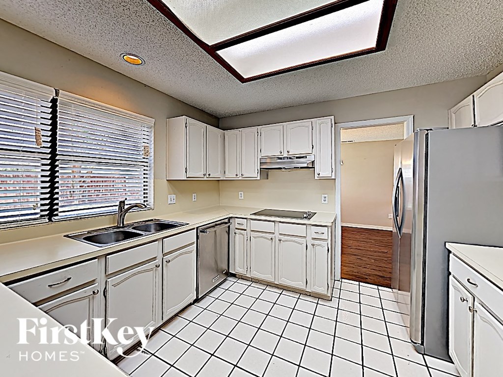 A kitchen with white cabinets and a black and white tiled floor.