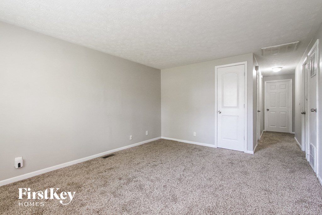 A carpeted room with a door on the right side.