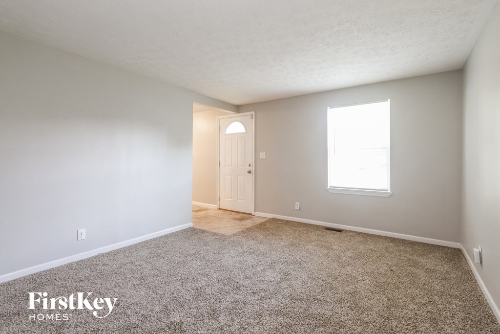 A carpeted room with a door and a window.