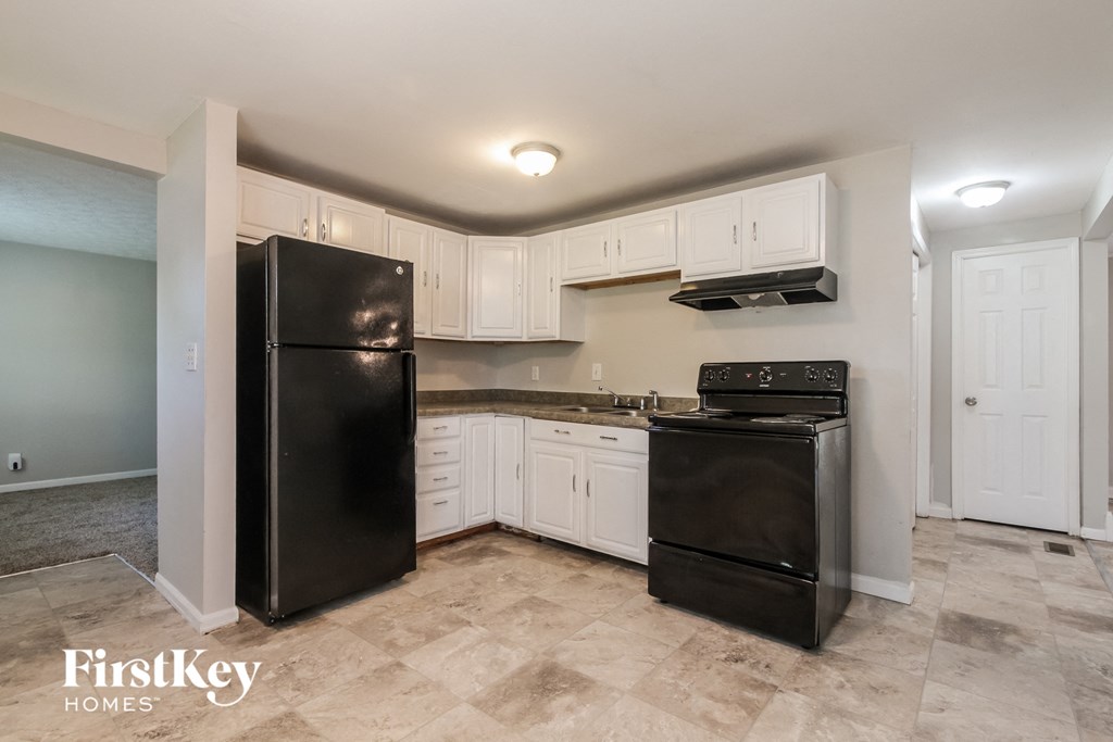 A kitchen with black appliances and white cabinets.