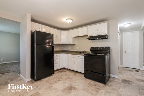 A kitchen with black appliances and white cabinets.