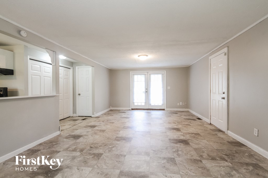 A spacious empty room with tile flooring and white walls.