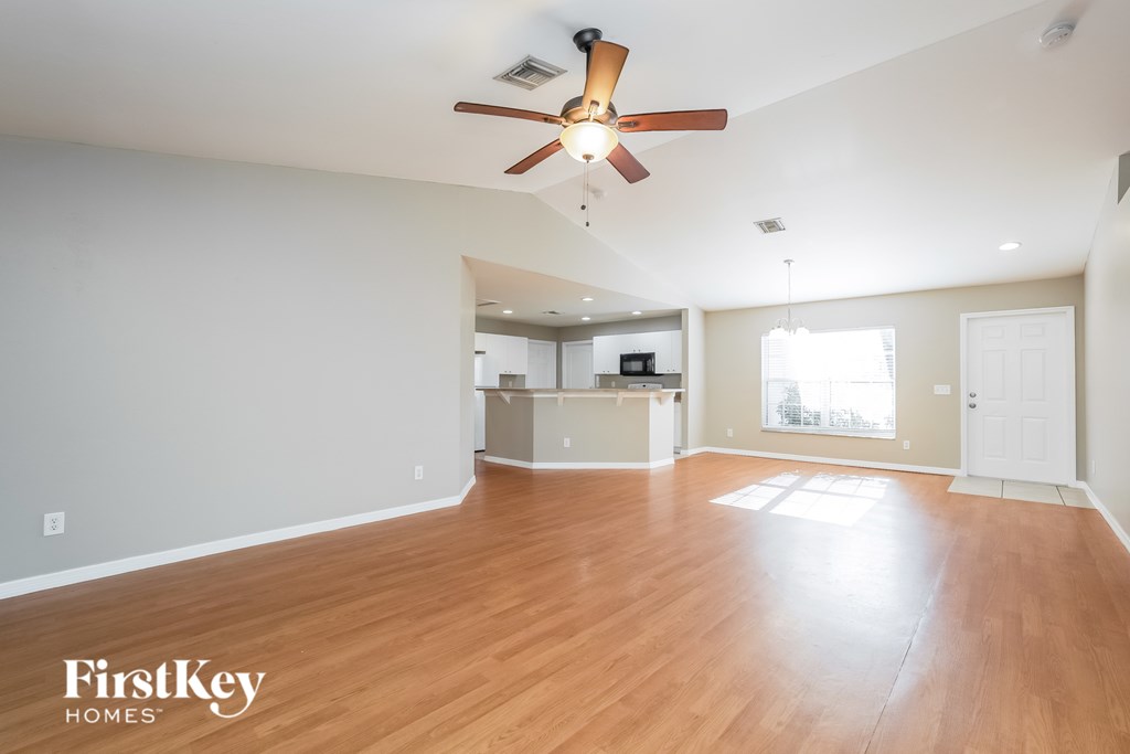 A spacious room with a ceiling fan and wooden flooring.