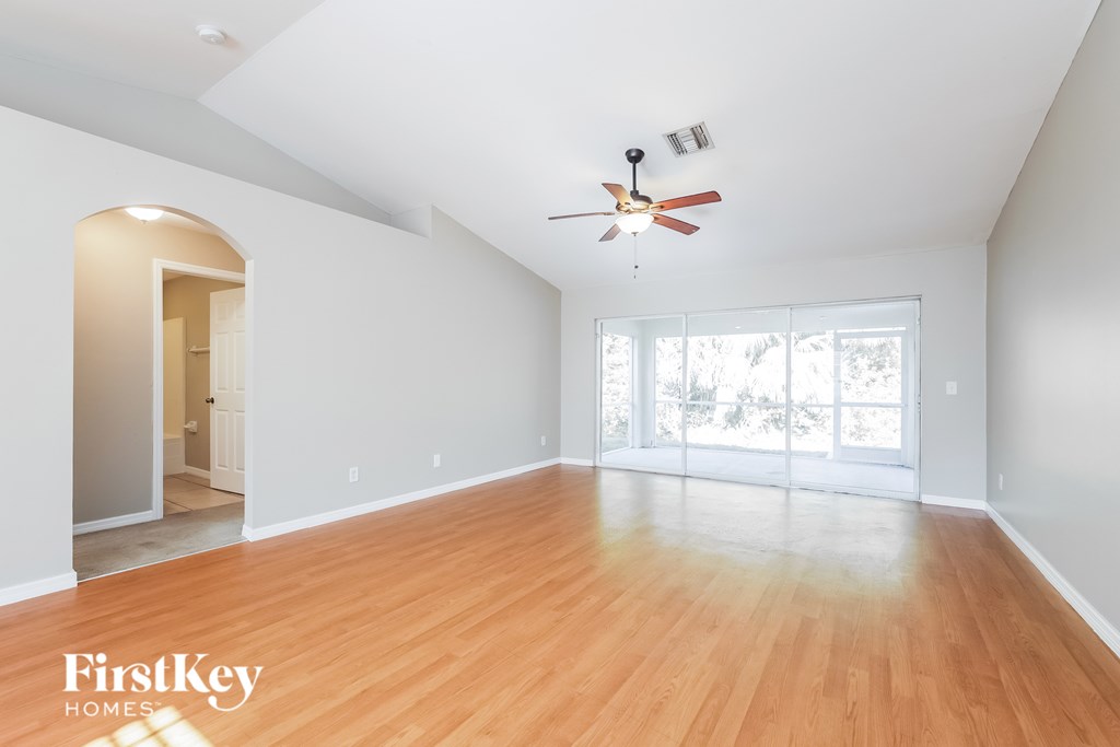 A spacious room with a fan and wooden flooring.