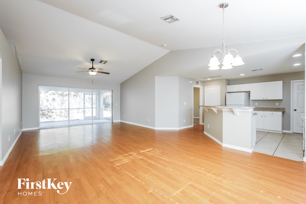 A spacious empty room with wooden floors and a ceiling fan.