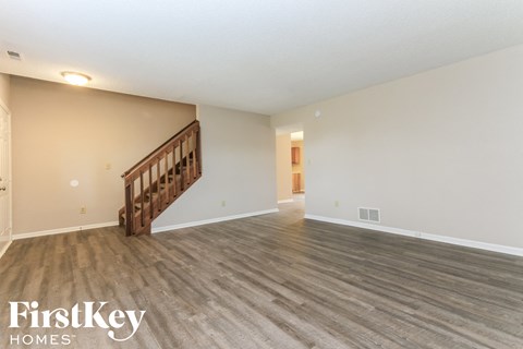 the living room and dining room with wood floors and white walls