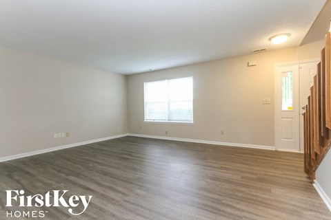 an empty living room with wood floors and a window