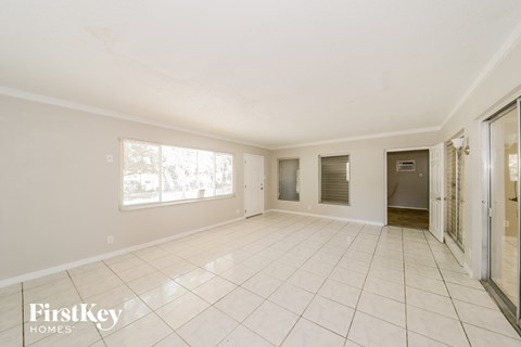A spacious empty room with tiled flooring and white walls.