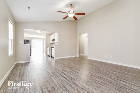 the living room and kitchen of an empty house with a ceiling fan