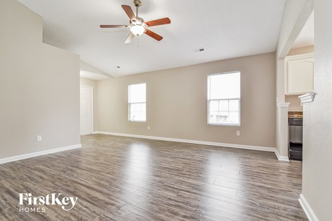 the spacious living room with hardwood floors and a ceiling fan