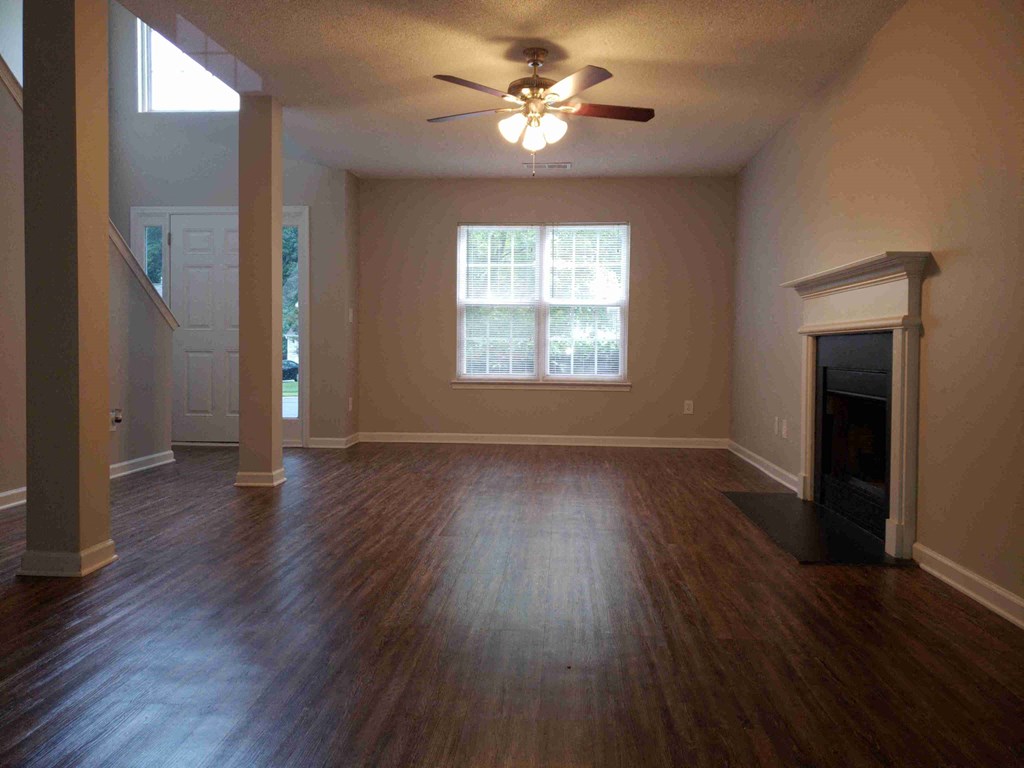 an empty living room with a ceiling fan