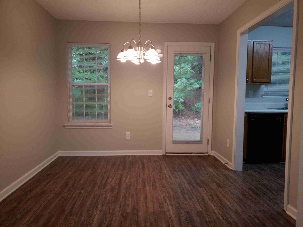 an empty living room with a door to a kitchen