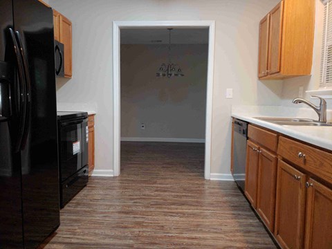 a kitchen with wooden cabinets and a black refrigerator and a sink