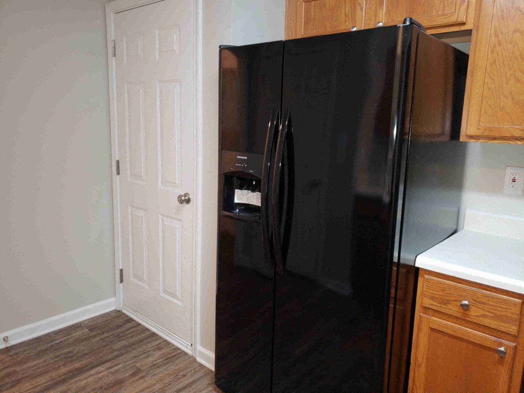 a black refrigerator in a kitchen with a white door