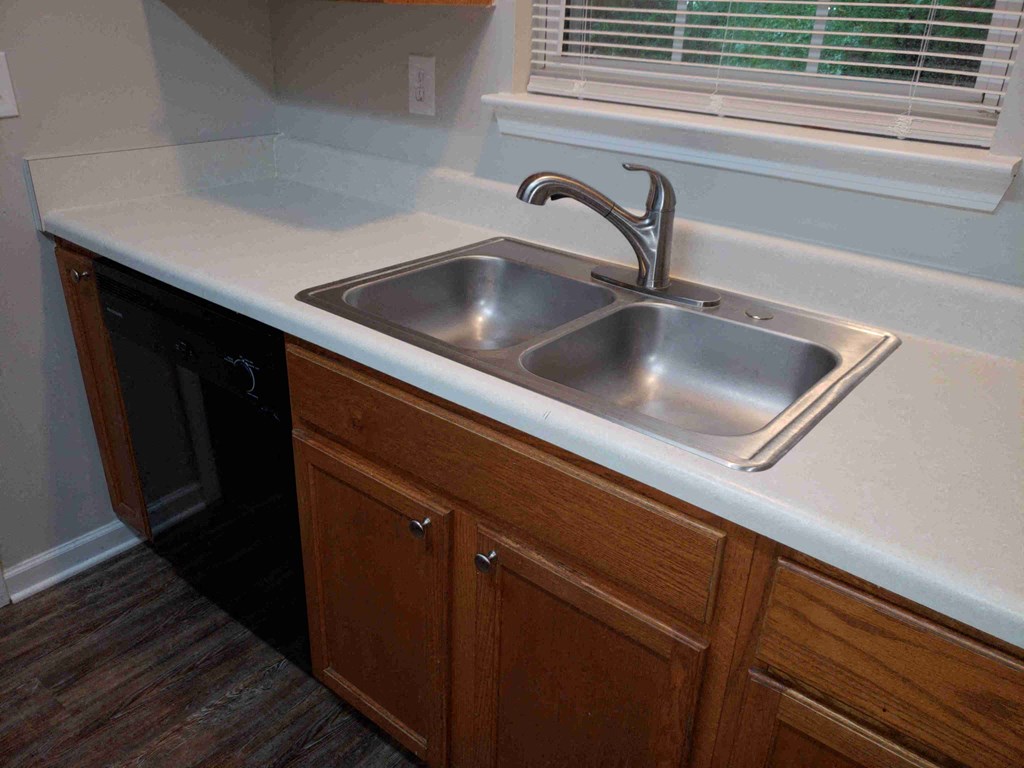 a stainless steel sink in a kitchen with wooden cabinets