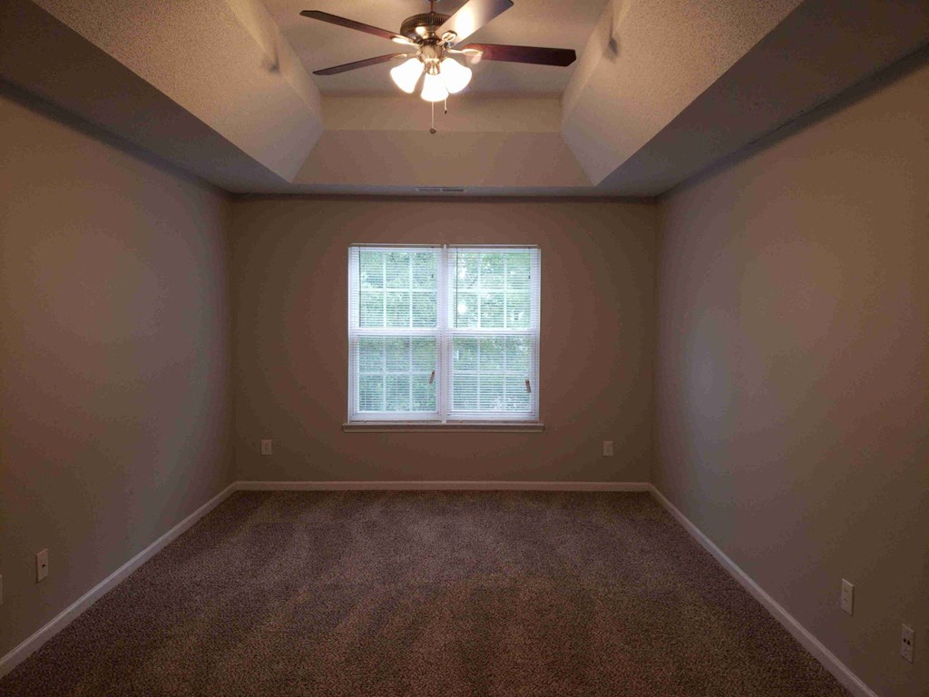 an empty room with a window and a ceiling fan