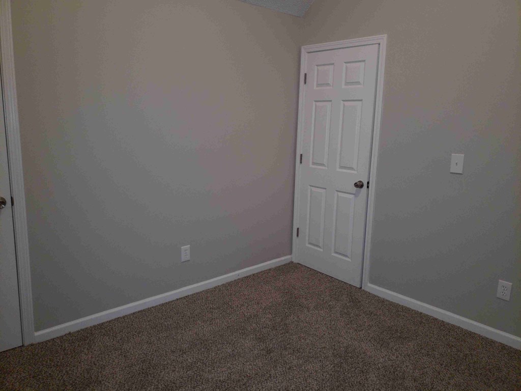 an empty room with a white door and carpet