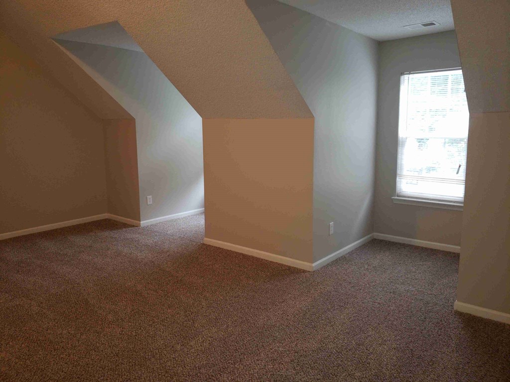 an empty room with white walls and brown carpet and a window