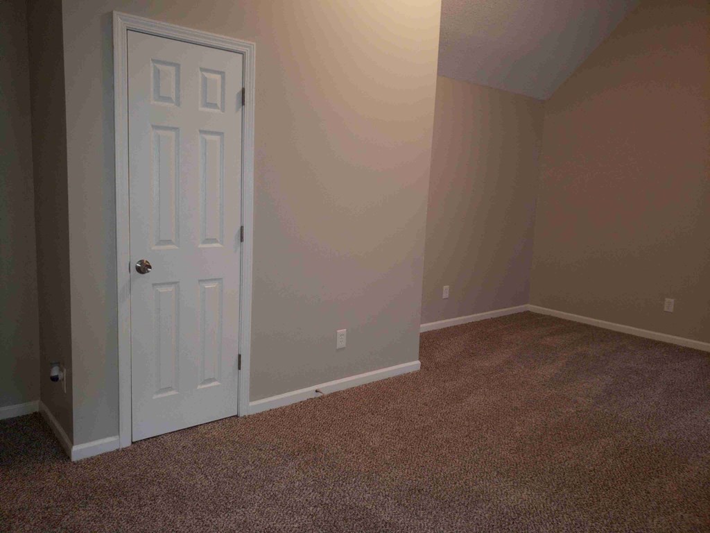 an empty room with a white door and carpet