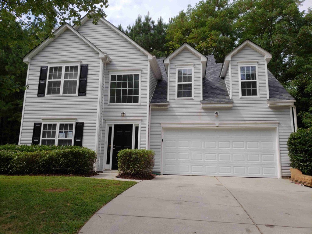 a white house with a garage door and a driveway