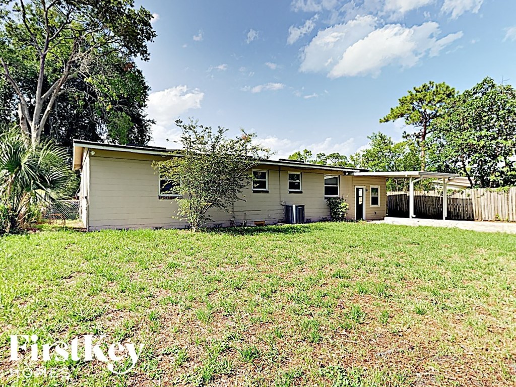 a small yellow house with a yard and a fence