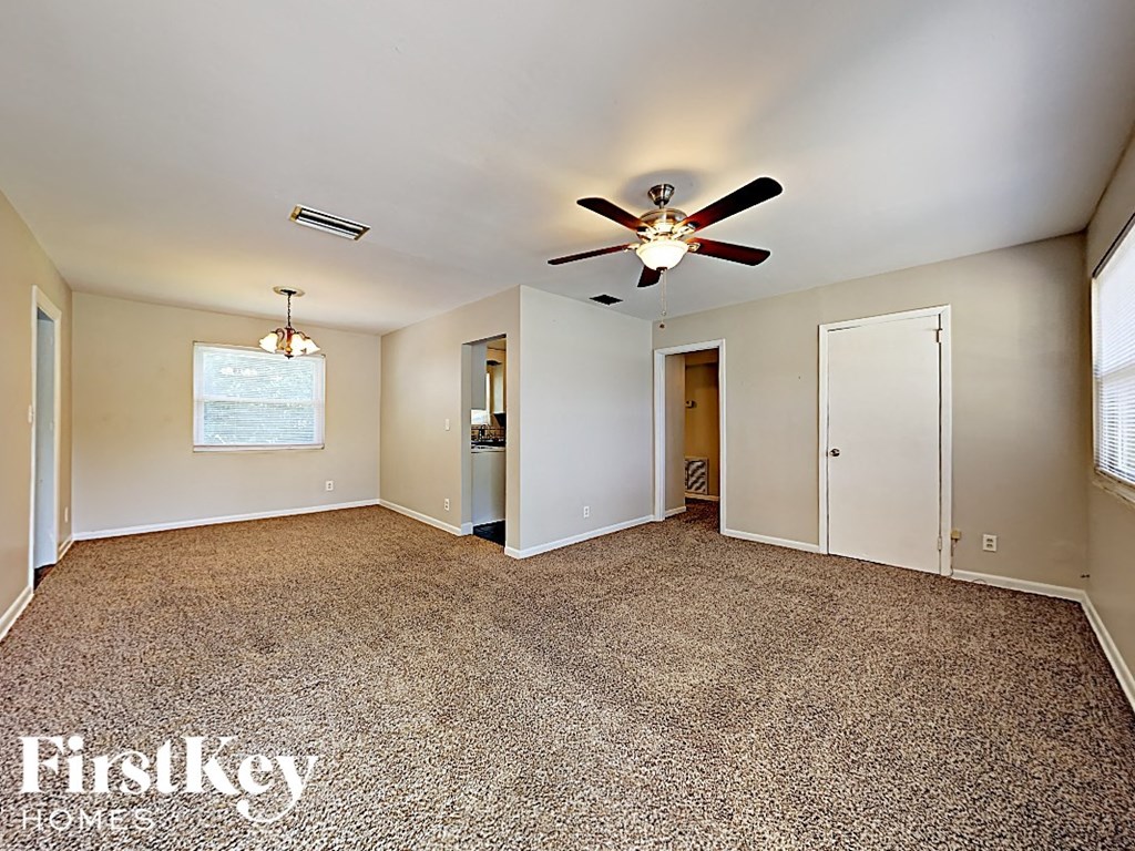an empty living room with a ceiling fan and a closet