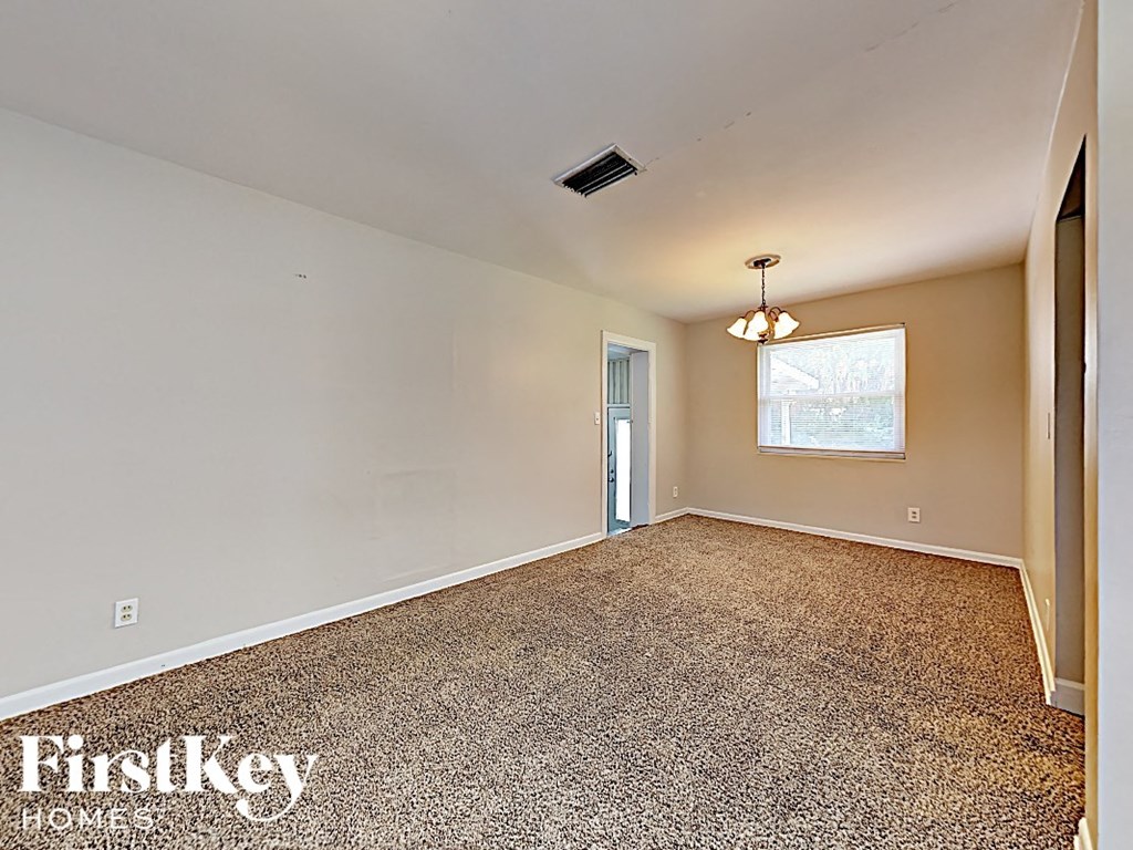an empty living room with a chandelier and a window